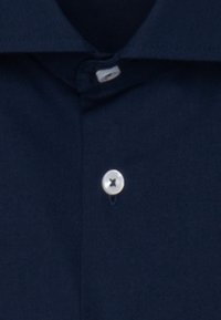 Camicia blu navy con bottoni e colletto standard, caratterizzata da un bottone argentato e una texture del tessuto liscia, che mette in risalto il design pulito.