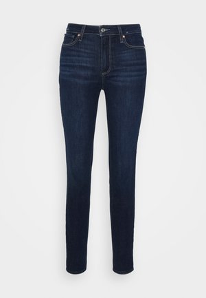 Tummansiniset slim fit -farkut, joissa etunappi ja vetoketju, edessä ja takana taskut sekä hienovaraiset saumaustiedot.