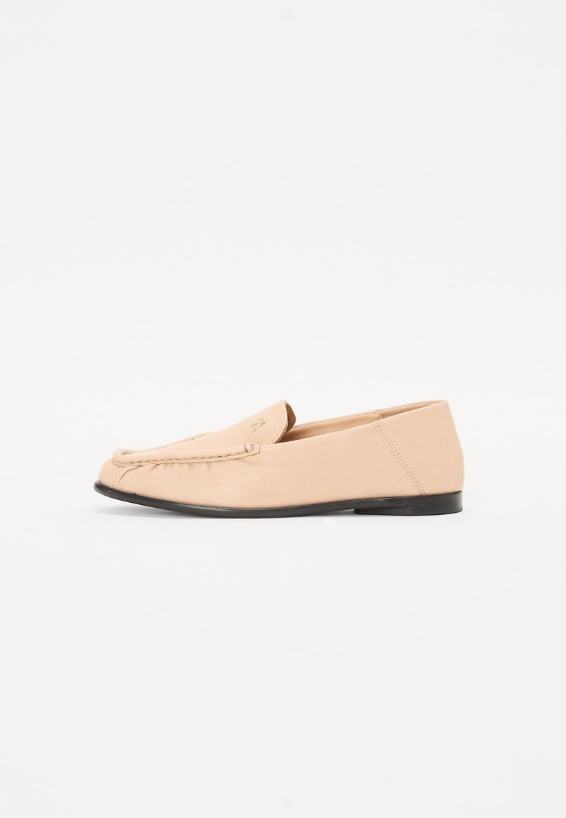 Beige læder loafers med syet detaljer, en flad sort sål og en rund tå. Minimalistisk design uden fremtrædende hardware eller accenter.