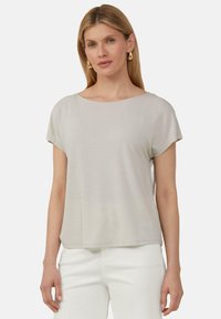 Jasnoszary t-shirt z krótkim rękawem, okrągłym dekoltem, miękką fakturą i luźnym krojem; zestawiony z białymi spodniami, prezentując casualowy outfit.