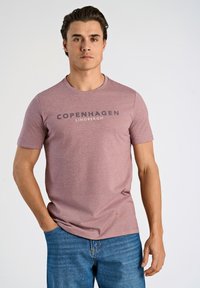 Tummanpunainen melange T-paita pyöreällä pääntiellä ja lyhyillä hihoilla, jossa on voimakas "COPENHAGEN LINDBERGH" -logo tummanharmaana rinnassa.