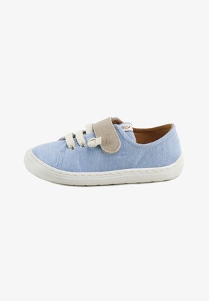 Zapatilla deportiva casual azul claro con tira de velcro beige, cordones color crema, suela de goma blanca y forro interior marrón, vista de lado.
