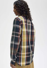 Camicia a maniche lunghe, a quadri multicolori in blu navy, giallo e bordeaux, dallo stile dritto, con polsini abbottonati e spacchi laterali.
