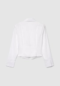 White cropped shirt with long sleeves, collar, and buttoned cuffs. Smooth fabric with a clean, simple design and back seam detail.