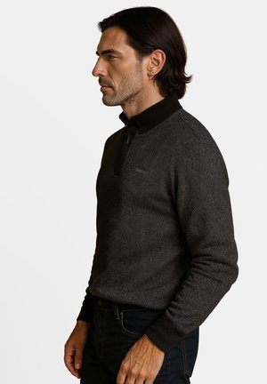 Pull marine gris foncé en tissu tricoté texturé, avec un col zippé, des poignets côtelés et un logo de marque discret sur la poitrine.