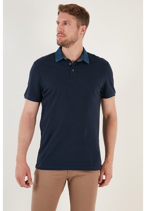 Polo din navy cu guler din denim, mâneci scurte și ușor elastic. Are două butoane la gât și un tiv drept.