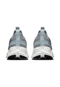 Baskets de sport grises avec une tige en mesh texturé, semelle en caoutchouc blanche et un onglet distinctif au niveau du talon. Présentent des rayures latérales bleu clair.