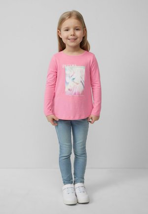 Różowa koszula z długim rękawem z grafiką jednorożca i napisem "MARZENIA". Połączona z jasnoniebieskimi skinny jeansami i białymi trampkami.