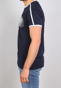 Námořnické tričko s b�ílými akcenty a průhlednou kapsou na hrudi. Krátké rukávy a přiléhavý střih. Bavlněný materiál.