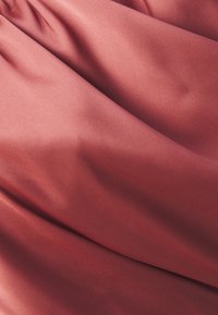 Gazdag rózsavörös árnyalatú textil, sima, fényes felülettel, amely puha redőzést és finom fényt mutat, elegáns hullámokkal.