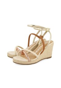 Sandalias de cuña beige con suela de yute, que presentan correas metálicas en oro rosa y marrón. Textura suave con correa de tobillo ajustable.
