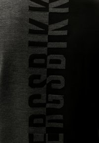 Tessuto a maglia grigio scuro e nero con testo verticale audace che recita "FEDERAZIONE" diviso a metà da colori in contrasto.