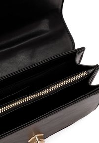 Bolso de piel negra con cremallera y herrajes dorados. El interior presenta múltiples compartimentos para organización, con una textura suave.