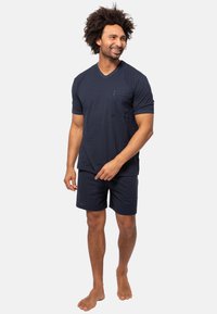 Marineblå kortærmet V-hals T-shirt med vandrette striber, parret med matchende shorts. Materialet ser blødt og afslappet ud.