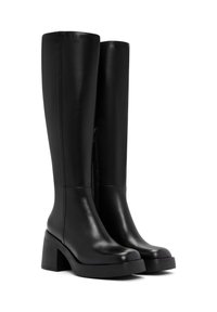 Bottes noires jusqu'aux genoux en cuir lisse avec un talon épais et une plateforme. Leur zip latéral facilite l'enfilage.