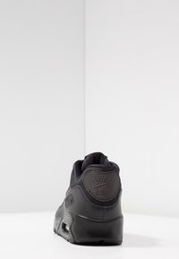 Czarne sneakersy Nike Air z materiału skórzanego i siateczkowego, o zaokrąglonym kształcie, wyściełanym kołnierzu oraz teksturowanym logo na pięcie.