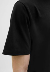 Schwarzes Baumwoll-T-Shirt mit Rundhalsausschnitt und kurzen Ärmeln. Der Stoff ist glatt und hat einen subtilen Glanz. Der Saum hat einen sauberen, genähten Abschluss.