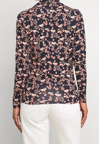 Marinblå långärmad skjorta med blommönster i gräddfärgad och röd. Mjuk tygkvalitet med figursydd design och sidoflikar för ökad komfort.