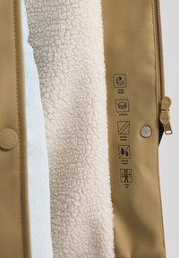 Tan padded jacket with a soft white fleece lining, features windproof and waterproof materials, two-way zipper, and clear care symbols.