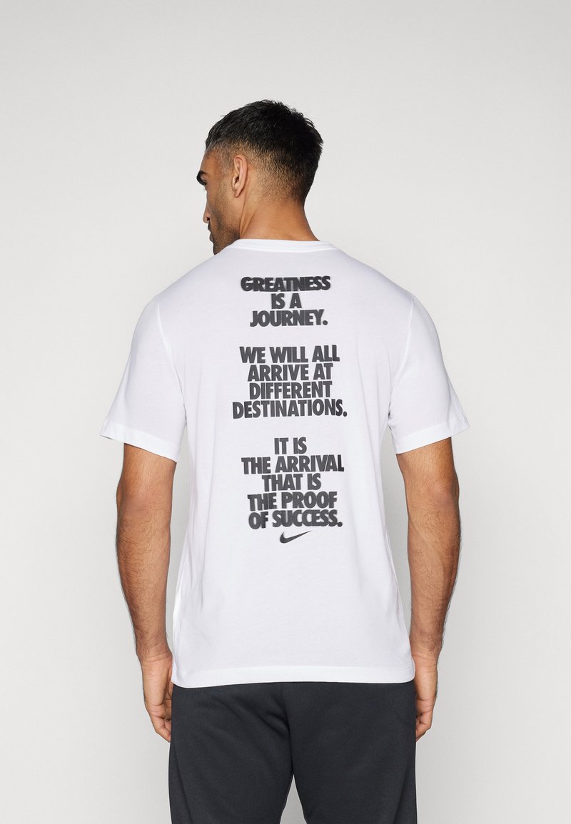 Camiseta blanca de algodón con texto negro en la espalda que incluye frases motivadoras. Cuello redondo clásico y mangas cortas. Logotipo de Nike en la parte inferior.