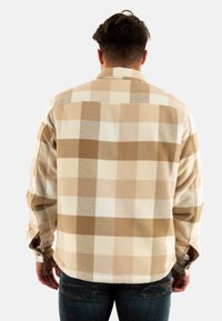 Knoopshirt in beige en crème ruitpatroon, met een zachte textuur, lange mouwen en een afgeronde zoom. Gefocuste weergave van het achterontwerp.