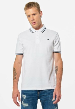 Polo shirt blanc en coton avec une couleur unie, col et poignets contrastés en marine, arborant un petit logo sur la poitrine gauche.