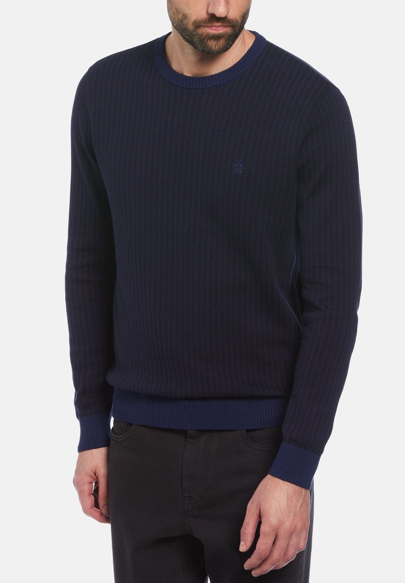 Pull en tricot bleu marine avec un motif texturé, col rond et poignets et ourlet côtelés. Petit logo brodé sur la poitrine.