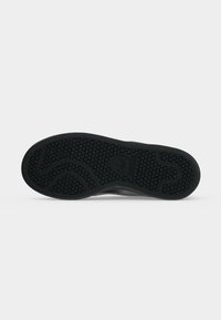 Čierna podrážka topánky Adidas so šesťuholníkovým vzorom dezénu a logom Adidas v strede na jednoduchom bielom pozadí.