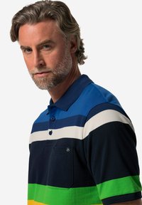 Polo triko s vodorovnými pruhy v modré, bílé, námořnické, zelené a žluté barvě. Krátké rukávy, límeček a detail kapsy na prsou.