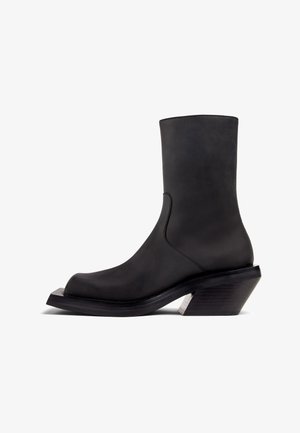 Black leather ankle boot with a rounded toe, smooth texture, and a chunky heel design. Features a silver accent on the heel.