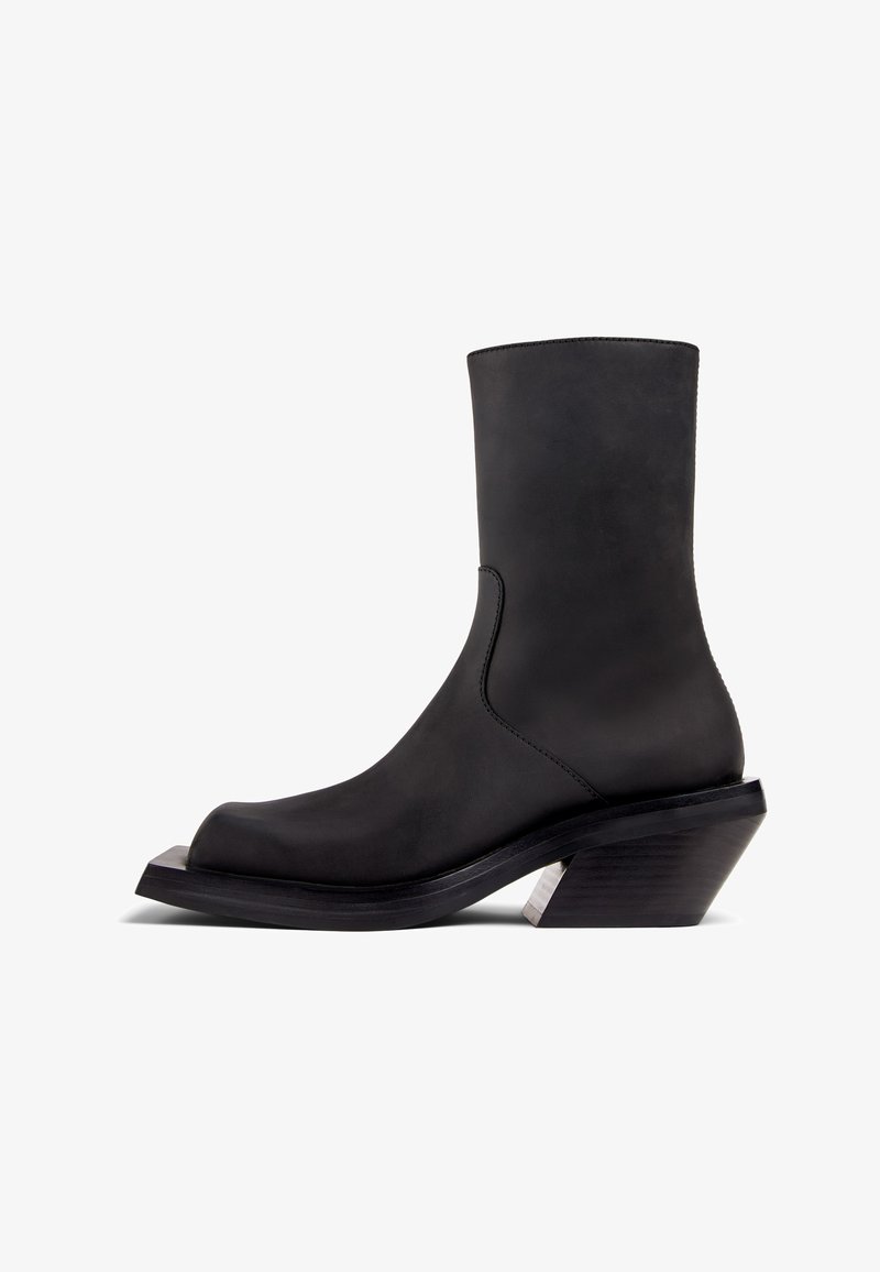 Czarne skórzane botki za kostkę z okrągłym noskiem, gładką fakturą i masywnym obcasem. Posiadają srebrny akcent na obcasie.