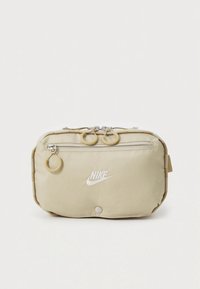 Nike smėlio spalvos audinio krepšelis su užtrauktuku, ant priekinės dalies - logotipas, du apskriti užtrauktukų trauktukai ir šoninė kilpa. Lygus paviršius, stačiakampio formos.