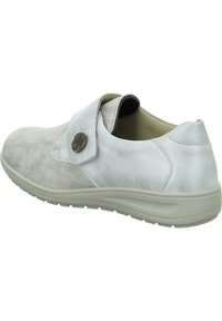 Hellgrauer Schuh mit einem strukturierten Stoffoberteil und glatten Lederakzenten. Verfügt über einen seitlichen Riemen mit einem runden Metallknopf und eine geschwungene Sohle.