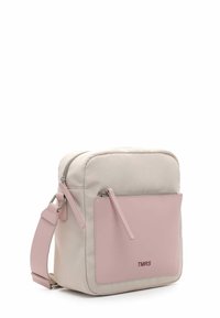 Crossbody bag in light beige fabric with a smooth pink leather front pocket. Features a silver zipper and an adjustable strap. Logo on pocket.