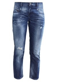 Modré džíny z denimu s opotřebovaným vzhledem, které mají vybledlé oblasti, roztržené akcenty a klasický střih s pěti kapsami.