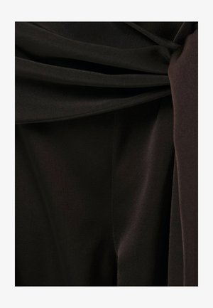 Detail měkké, tmavě hnědé látky s hladkými sklady a mírným leskem.