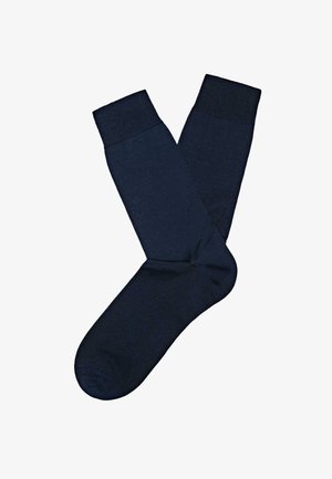 Par sorte mørkeblå crew-strømper med ribbede manchetter, lagt fladt ud med den ene en smule overlappende den anden på en hvid baggrund.