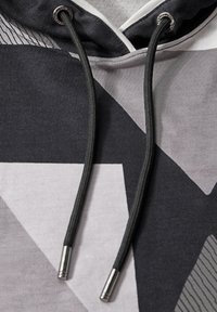 Hoody met een geometrisch patroon in zwart, grijs en wit. Beschikt over een tweekleurige stof, trekkoorden en metalen uiteinden aan de koorden.