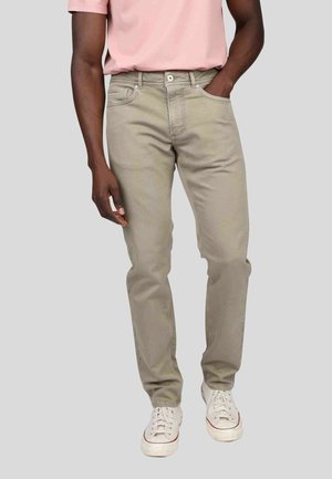 Jeans beige clair avec une coupe droite, cinq poches et des détails de couture subtils. Associés à des baskets blanches et un t-shirt rose.