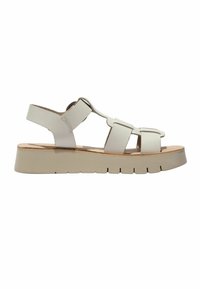 Beige flat sandal with thick straps, open toe, and a hook-and-loop ankle strap on a segmented rubber sole.