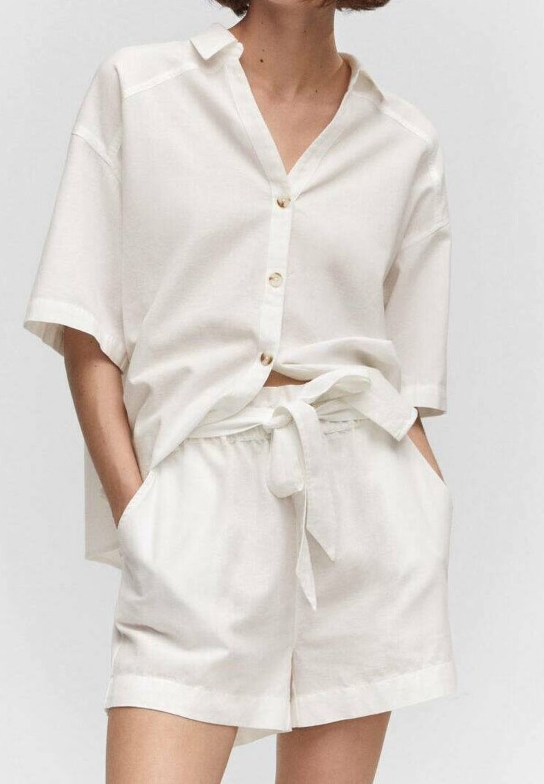 Chemise en lin blanc à manches courtes et boutonnée sur le devant, associée à un short assorti avec une ceinture nouée et des poches latérales. Design simple.