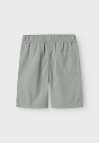 Shorts vert clair avec une taille élastique, une poche arrière unique et une texture de tissu lisse. Coupe droite avec un design minimaliste.