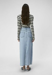 Striped knit sweater with long sleeves paired with a high-waisted light blue denim skirt featuring two back pockets and a straight silhouette.