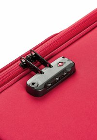 Red suitcase with a textured surface, featuring a black TSA lock and zipper. Lock includes dials and a keyhole for security.