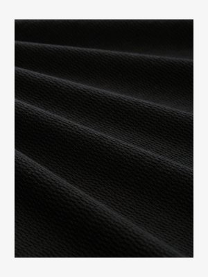 Black textured fabric with a ribbed pattern, showcasing multiple folds and waves, emphasizing a matte finish and durable appearance.