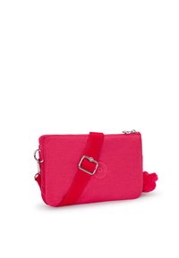 Pouch-style bag in bright pink fabric, featuring a red strap, silver hardware, and a pom-pom accent. Smooth texture with logo detail.