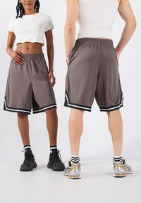Shorts de sport gris avec des accents rayés noirs et blancs, en matériau léger et avec une taille élastique, portés par deux personnes.