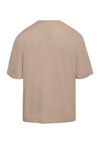 Camiseta de algodón beige con cuello redondo, mangas cortas y un corte holgado. Textura suave con una construcción simple y sin patrones visibles.