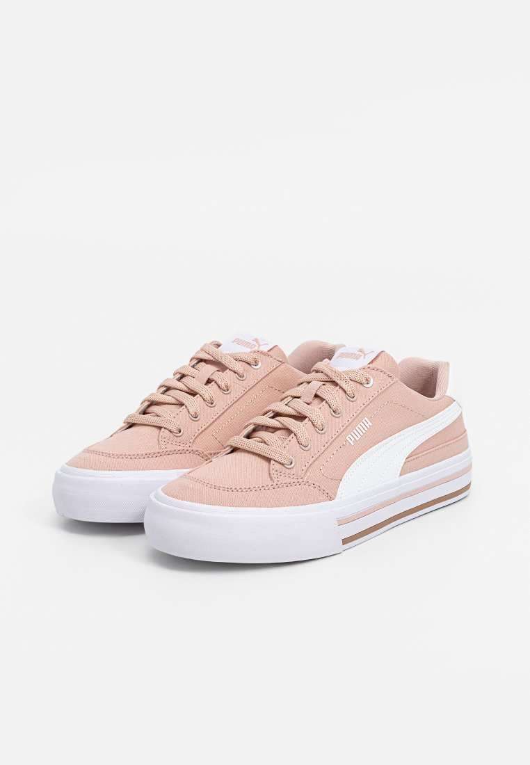 Een paar roze low-top Puma sneakers met een witte streep en dikke witte zolen op een witte achtergrond.