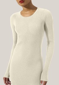 Abito a maniche lunghe in maglia rigata color beige chiaro, con scollatura rotonda e silhouette aderente, caratterizzato da maniche con polsini allungati.